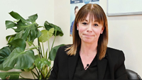 une femme assise à un bureau devant une plante.